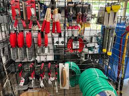 Organic workshop display of professional USA Brands gardening tools including forged shovels, pruners, and brass hose on cedar workbench